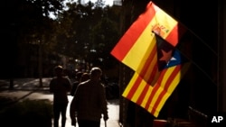 People walk past a Spanish and an estelada, or independence flag, hanging up for sale in a shop in Barcelona, Spain, Oct. 11, 2017. 