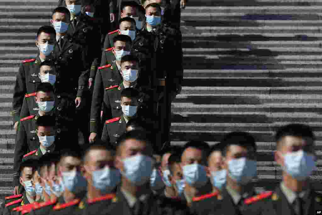 Chinese paramilitary policemen wearing face masks to help curb the spread of the coronavirus march down a staircase outside the Great Hall of the People after attending the commemorating conference on the 70th anniversary of China&#39;s entry into the 1950-53