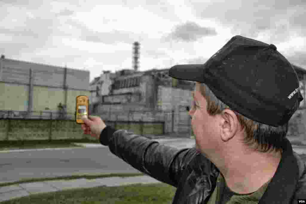O motorista Igor Bordnarch, visitante frequente do local do reactor de Chernobyl, verifica a radiação a apenas 240 metros do reactor destruído, fábrica de Energia Nuclear de Chernobyl, Ucrânia, Março 19, 2014. (Steve Herman/VOA)