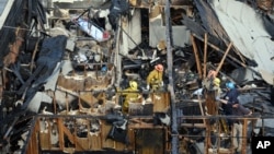 A ladder truck lifts a body, one of four additional bodies found in the burned-out ruins of an abandoned office building in the Westlake district just west of downtown Los Angeles Tuesday, June 14, 2016.