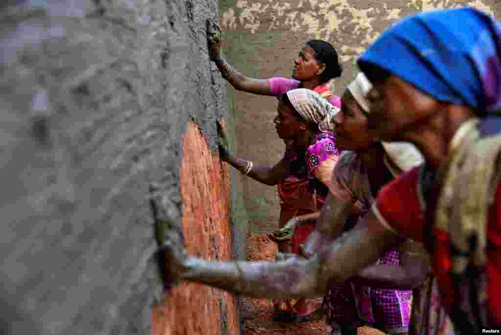 Laborers coat bricks with a mixture of mud and cow dung in a brick kiln at Langolpota village in the eastern state of West Bengal, India, Nov. 26, 2019.