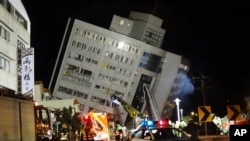 Rescuers are seen entering a building that collapsed onto its side from an early morning 6.4 magnitude earthquake in Hualien County, eastern Taiwan, Wednesday, Feb. 7 2018. Rescue workers are searching for any survivors trapped inside the building.