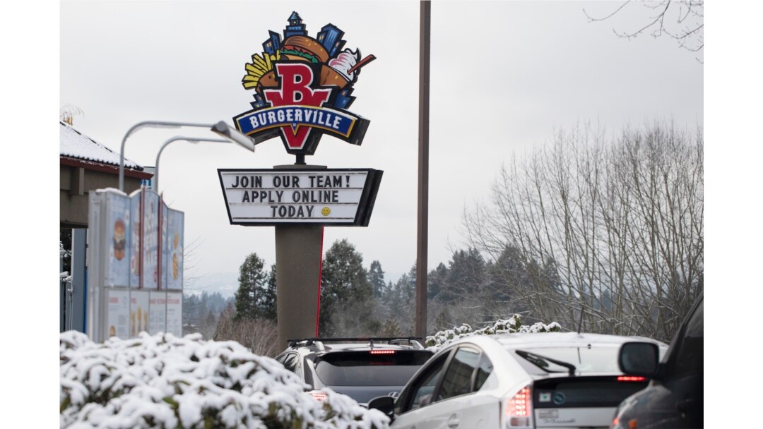 FILE - A sign seeking workers is displayed at a fast food restaurant in Portland, Oregon, Dec. 27, 2021.