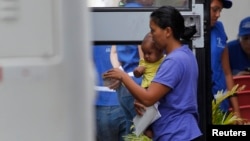 A woman and her son step into a bus, bound to take deportees from U.S. to a bus station, at the international airport in San Pedro Sula, northern Honduras July 14, 2014.