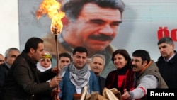 Selahattin Demirtas (front C), co-chairman of the pro-Kurdish Peace and Democracy Party (BDP), lights a traditional Newroz fire during a rally to celebrate the spring festival of Newroz - with a picture of imprisoned PKK leader Abdullah Ocalan seen in the