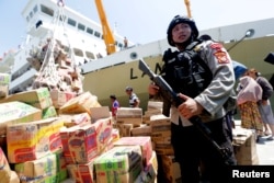 A policeman secures the transfer of food and aid for victims following a quake and tsunami at Pantoloan port in Palu, Central Sulawesi, Indonesia, Oct. 1, 2018 in this photo taken by Antara Foto.