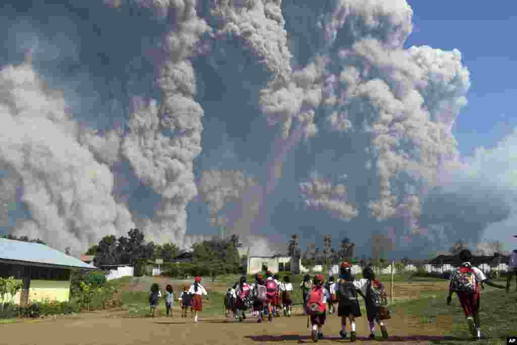 School children walk as Mount Sinabung erupts in Karo, North Sumatra, Indonesia.