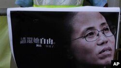 一名抗议者手举诺贝尔和平奖得主刘晓波的遗孀刘霞的照片在北京驻香港中联办外举行示威，要求立即释放被软禁的刘霞。（2017年7月13日）