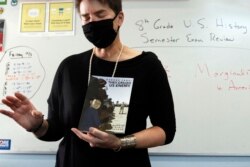 FILE - History teacher Wendy Leighton holds a copy of 'They Called us Enemy,' about the internment of Japanese Americans, while speaking about marginalized with her students at Monte del Sol Charter School, Dec. 3, 2021, in Santa Fe, N.M.