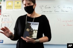 FILE - History teacher Wendy Leighton holds a copy of 'They Called us Enemy,' about the internment of Japanese Americans, while speaking about marginalized with her students at Monte del Sol Charter School, Dec. 3, 2021, in Santa Fe, N.M.