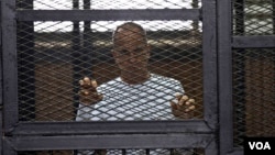 Al-Jazeera English correspondent Peter Greste appears in a defendant's cage in a courtroom in the Police Institute Court House in Tora, along with several other defendants during their trial on terror charges, in Cairo, Egypt, April 22, 2014. (Hamada Elra