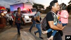 Decenas de migrantes que buscan llegar a Estados Unidos caminan por una carretera mientras salen de San Pedro Sula, Honduras, al amanecer del martes.