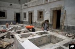 A worker restores a stone wash basin that for centuries was used to store water and for cleaning clothes, in the courtyard of 25 Manzanares Street, in Mexico City, Sept. 10, 2018.