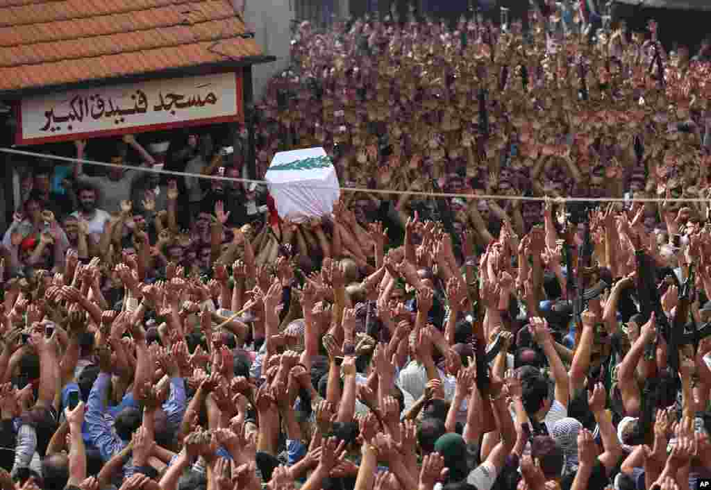 Lebanese mourners raise up their hands and weapons as others carry the coffin of Sgt. Ali Sayid who was beheaded by Islamic militants, during his funeral procession at his home town of Fnaydek, in Akkar north Lebanon. Sgt. Ali Sayid went missing around the same time that some two dozen soldiers and police were seized by militants from Syria who overran the border town of Arsal for several days last month.