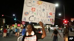 Una mujer californiana porta un letrero que dice "Ser negro no es un crimen" en Los Ángeles. Por tercera noche consecutiva hubo violencia en esa ciudad por el veredicto absolutorio de George Zimmerman.
