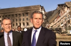 President George W. Bush, accompanied by Secretary of Defense Donald Rumsfeld (L), speaks in front of the west side of the Pentagon on September 12, 2001.