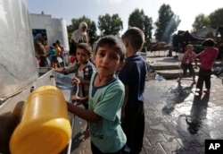 Displaced Palestinian children collect water at the Abu Hussein U.N. school in Jebaliya refugee camp, northern Gaza Strip, on July 30, 2014. It had been hit by artillery shells earlier in the day.