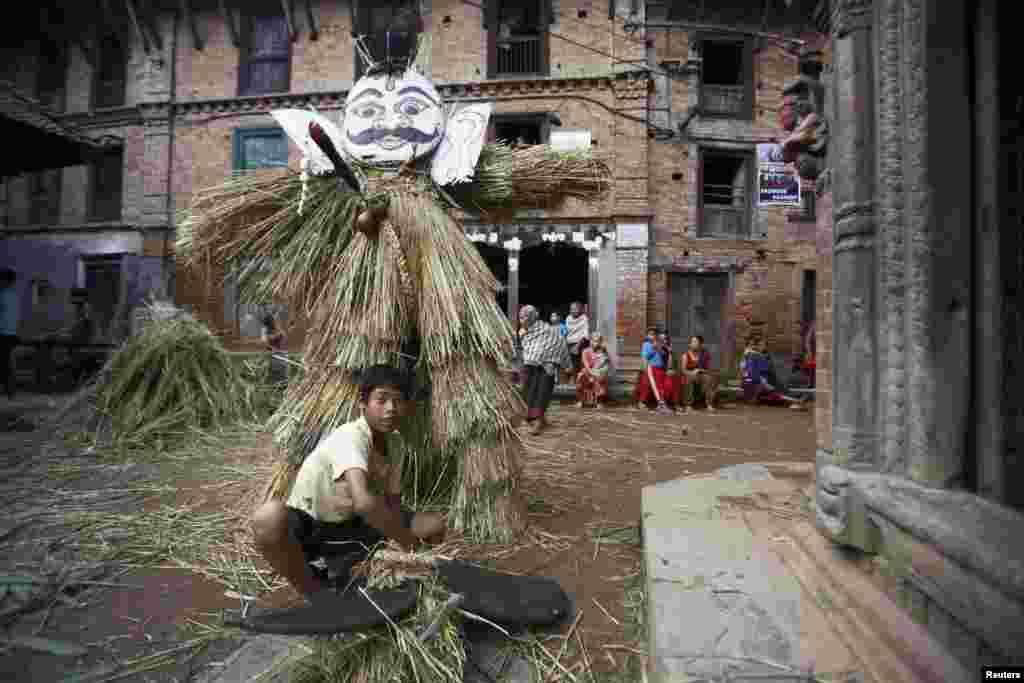 A boy makes an effigy of demon Ghantakarna before it is burned to symbolize the destruction of evil during the Ghantakarna festival at the ancient city of Bhaktapur, Nepal.