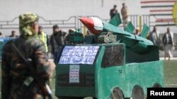 A Houthi militant stands in front of a cardboard model of a missile during a gathering to mark 1,000 days of the Saudi-led military intervention in the Yemeni conflict, in Sanaa, Yemen, Dec. 21, 2017.