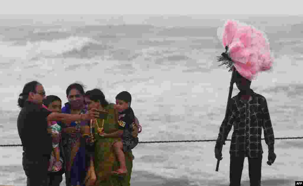 An Indian family takes a selfie next to a candy seller in a closed beach in Puri in the eastern Indian state of Odisha on May 2, 2019, as cyclone Fani approached the Indian coastline.