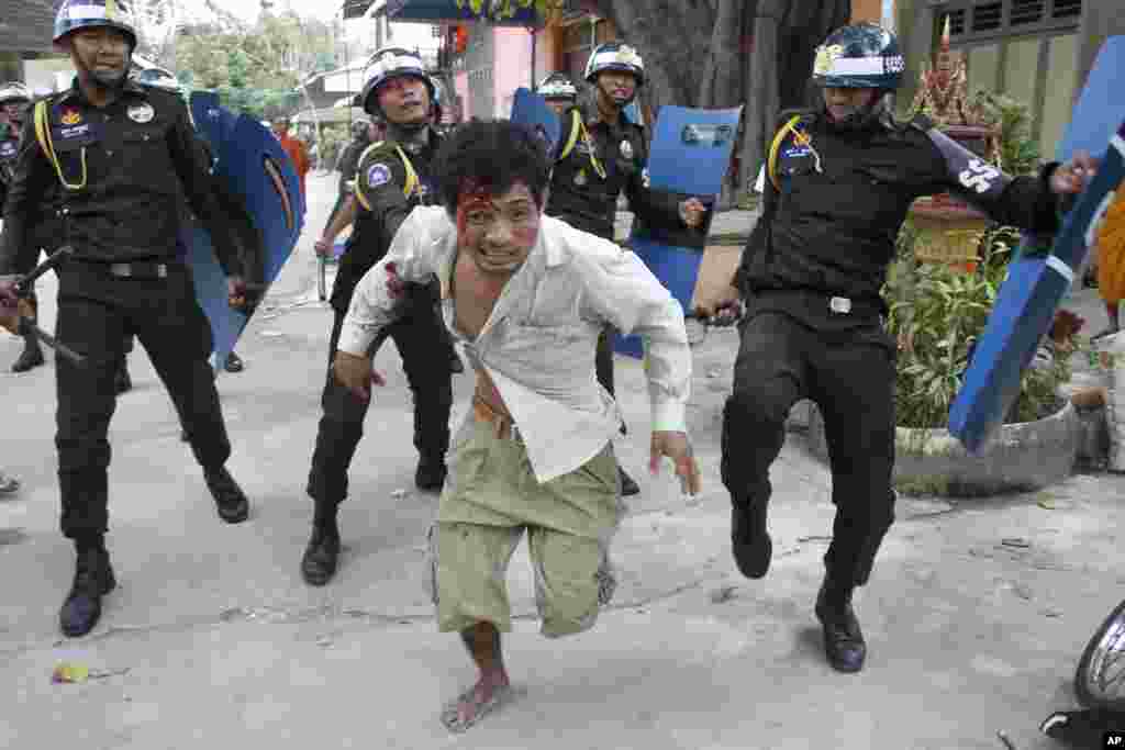 An injured worker escapes from riot police in the compound of a Buddhist pagoda in Phnom Penh, Cambodia, Nov. 12, 2013.