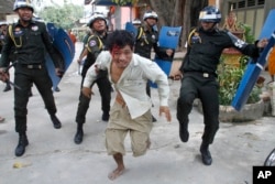 FILE - An injured worker escapes from riot police in the compound of a Buddhist pagoda in Phnom Penh, Cambodia, Nov. 12, 2013.