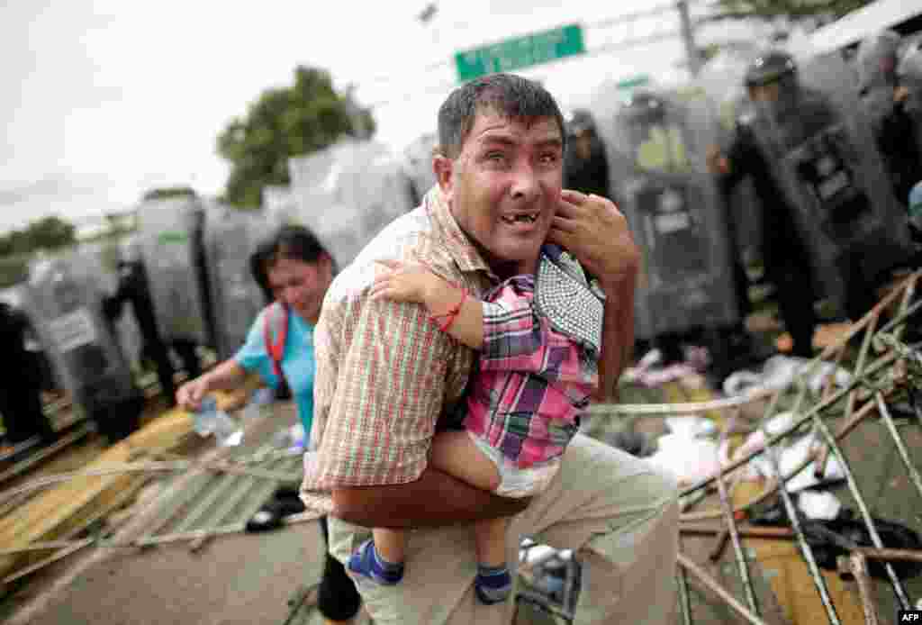 Un migrante protege a su hijo después de que otros migrantes asaltaran un punto de control fronterizo en Guatelama, Ciudad Hidalgo, México, el 19 de octubre del 2018. 