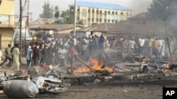 People gather at the site of a bomb explosion at a road in Kaduna, Nigeria on Sunday, April 8, 2012.