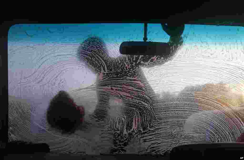 A boy cleans the windshield of a car early in the morning in Dhaka, Bangladesh. &nbsp;