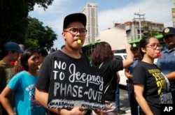 FILE - Supporters of public transport drivers blow their whistles to urge other drivers to join the planned two-day public transport strike nationwide to protest the government's phase out of the WWII-era passenger transport locally known as "jeepney" in Manila, Philippines, Oct. 16, 2017.