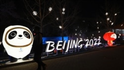 A man walks past installations of Bing Dwen Dwen,left, and Shuey Rhon Rhon, mascots of the Beijing 2022 Winter Olympics Games, along a street in Beijing on Jan. 28, 2022.