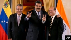 Venezuela's President Nicolas Maduro, center, and Executive Director of Oil and Natural Gas Corporation, Narendra Kumar Verma, flash victory hand signs as they pose for a photo in Caracas, Venezuela, Nov. 4, 2016. At right is PDVSA President Eulogio Del Pino. 