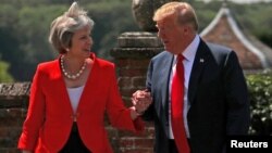 FILE - Britain's Prime Minister Theresa May and U.S. President Donald Trump walk to a joint news conference at Chequers, the official country residence of the prime minister, near Aylesbury, Britain, July 13, 2018.