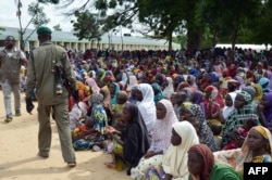 A policeman walks past dozens of people, who have been displaced from their communities after attacks by the Islamist group Boko Haram, at a camp for internally displaced people in Maiduguri, August 3, 2015.