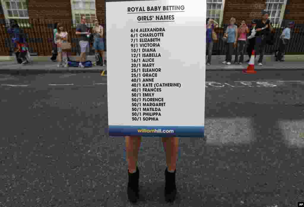 A bookmaker agency employee poses for the photographers with a board of odds regarding the royal baby&#39;s name near St. Mary&#39;s Hospital, London, July 17, 2013. 