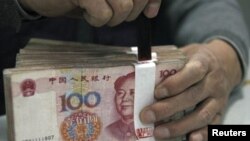 An employee seals a stack of yuan banknotes at a branch of Industrial and Commercial Bank of China in Huaibei, Anhui province, April 6, 2011.