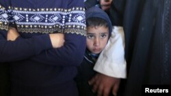 A boy looks at the body of Palestinian man, who, according to medics, died of wounds he sustained after he was shot by Israeli troops during clashes with Palestinian protesters on Friday, during his funeral in the central Gaza Strip, Dec. 28, 2015. 