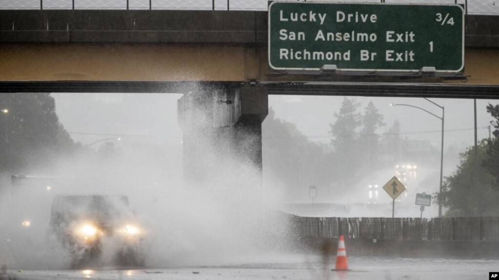 Un automóvil avanza en medio de una calle inundada el domingo 24 de octubre de 2021 en la carretera 101 de Corte Madera, California. (AP Foto / Ethan Swope)