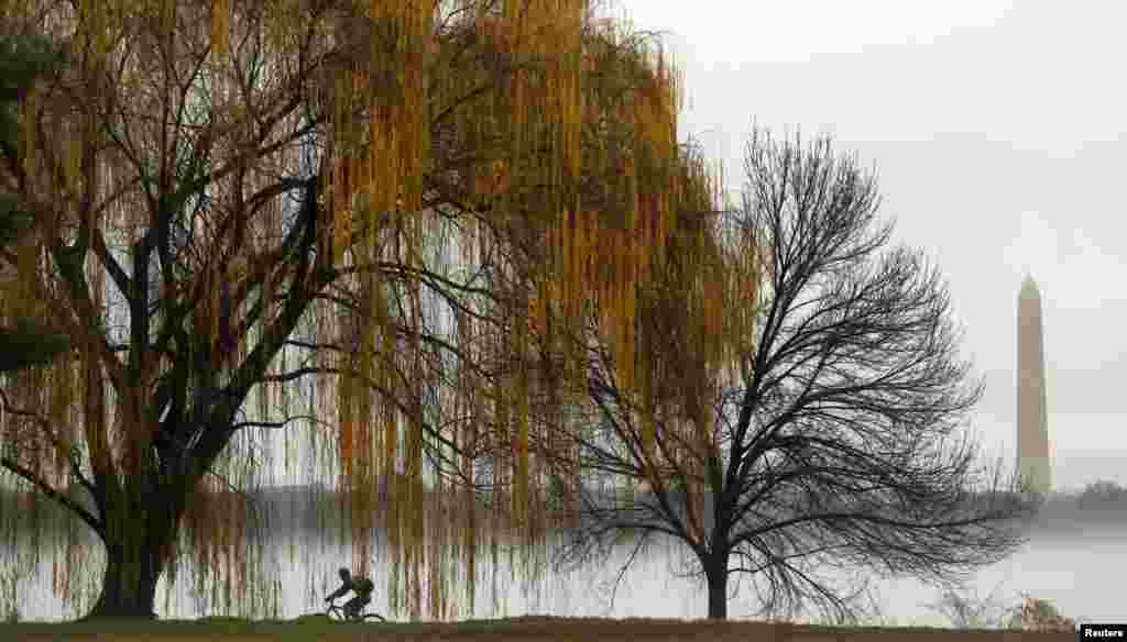 The Washington Monument is seen beyond a heavy fog clinging to the Potomac River as a cyclist makes his way along a riverbank path in Washington, D.C., Dec. 23, 2015.