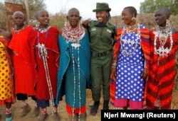 Sharon Karaine, anggota Team Lioness, sebuah unit ranger Kenya yang semuanya perempuan, disambut oleh wanita Maasai dengan kostum tradisional saat ia pulang dari kamp Risa, Amboseli, Kenya, 8 Agustus 2020. (Foto: REUTERS/Njeri Mwangi)