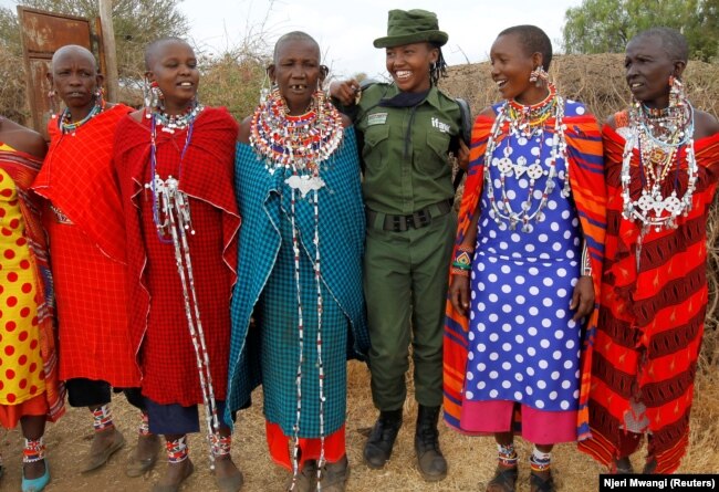 Sharon Karaine, anggota Team Lioness, sebuah unit ranger Kenya yang semuanya perempuan, disambut oleh wanita Maasai dengan kostum tradisional saat ia pulang dari kamp Risa, Amboseli, Kenya, 8 Agustus 2020. (Foto: REUTERS/Njeri Mwangi)
