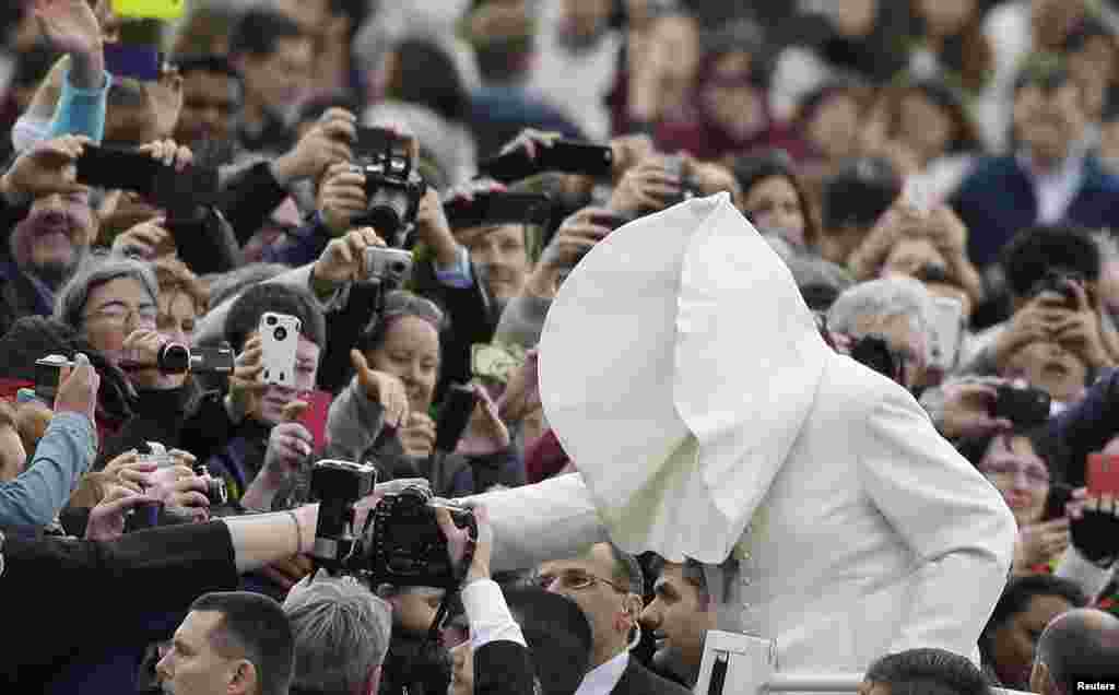 A gust of wind blows Pope Francis&#39;s mantle as he arrives to lead his Wednesday general audience in Saint Peter&#39;s square at the Vatican.