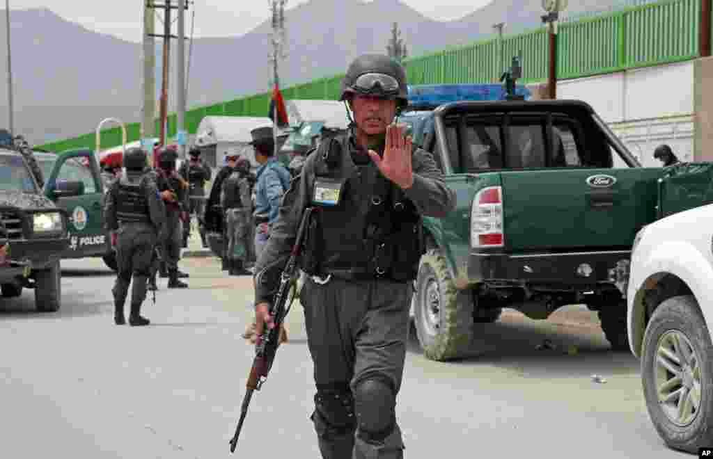 Seorang petugas polisi Afghanistan menghalangi wartawan mendekati Cure International Hospital di Kabul, Afghanistan, 24 April 2014.