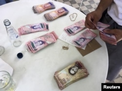 FILE - A waiter counts Venezuelan bolivar notes, corresponding to the bill for a lunch of 4 people, at a restaurant in Caracas, July 14, 2015.