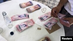 Una mesera cuenta bolívares con los que se pagaron un almuerzo para cuatro personas en un restaurante de Caracas.