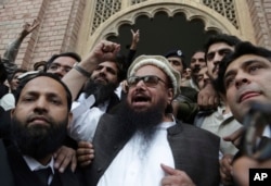 FILE - Hafiz Saeed, head of the Pakistani religious party Jamaat-ud-Dawa, gestures outside a court in Lahore, Pakistan, Nov. 22, 2017.