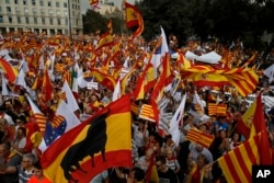 People wave flags of Catalonia and Spain as they celebrate a holiday known as "Dia de la Hispanidad" or Spain's National Day in Barcelona, Spain, Oct. 12, 2017.