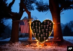 FILE - A makeshift memorial with crosses for the victims of the Sandy Hook massacre stands outside a home in Newtown, Dec. 14, 2013, the one-year anniversary of the shootings.