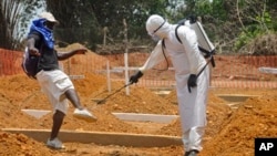 A man is sprayed with disinfectant after he celebrated the memory of a loved one who died due to the Ebola virus at a newly build grave yard for Ebola virus victims in Monrovia, Liberia, Wednesday, March 11, 2015. Liberians held a church service Wednesday