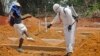 FILE - A man is sprayed with disinfectant after he celebrated the memory of a loved one who died due to the Ebola virus at a newly build grave yard for Ebola virus victims in Monrovia, Liberia, March 11, 2015. 